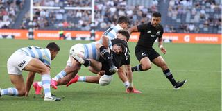 Argentina's Santiago Carreras (centre) tackles New Zealand's Beauden Barrett. 