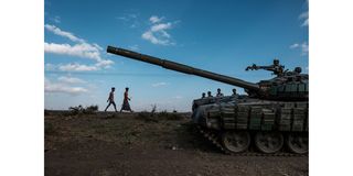 Youngsters walk next to an abandoned tank belonging to Tigrayan forces south of the town of Mehoni, Ethiopia, in December 2020.