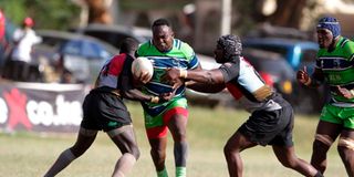 Oscar Simiyu of KCB is tackled by Patrice Agunda and Won Chebo of Kenya Harlequin