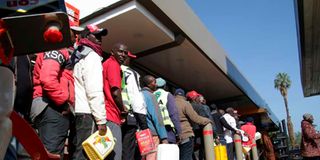 People queue to buy fuel at a filling station.