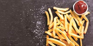 French fries with ketchup on a dark table.
