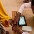 A polling clerk uses a Kiems kit to identify a voter.