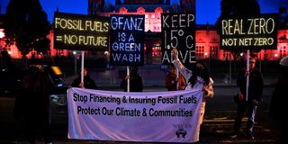 Climate activists hold illuminated signs and a banner protesting against the use of fossil fuels