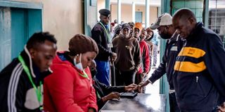 Voters queue to have their information verified on the Kiems kit.