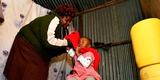 Bridgette Ndanu prepares her granddaughter Ruth Nyawira to go to school 