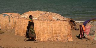 woman from the El Molo walks past makeshift houses 