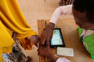 A polling clerk uses a Kiems kit to identify a voter.