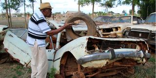 Andrew Githinji inspects the wreckage of his car outside a compound at Gwathamaki village in Nyeri county.