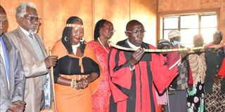 Reverend Joseph Kiplagat blesses a 'Sosiot' an instrument of power given to activist Jerotich Seii by her Kaplegenui clan 