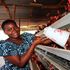 Anna Ndunda feeds chicken at Kambi Ya Mawe Village in Makueni County