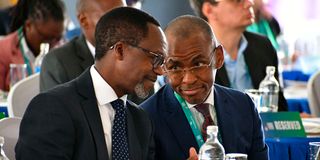 NCBA Group MD John Gachora (left) confers with Safaricom CEO Peter Ndegwa