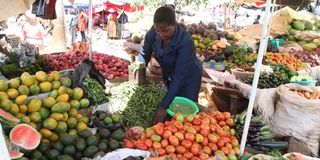 A trader sorts tomatoes at her stand at Chaka market in Nyeri County.