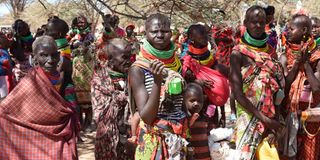 Locals wait for their rations of relief food distribution by President William Ruto