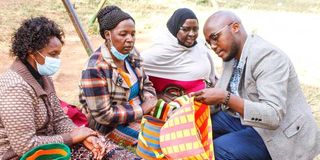 Eric Mutwiri, an economist, samples baskets made by women groups in Tharaka Nithi County.