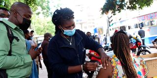 A woman receiving a Covid-19 vaccine at Kencom bus stop in Nairobi