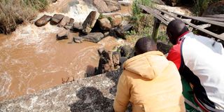 Residents look at an unidentified body that was floating in River Yala