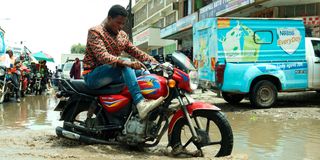 A boda boda rider maneuvers through a flooded section along First Avenue Eastleigh, Nairobi
