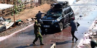 A man lobes a teargas canister into an empty vehicle that was part of the opposition leader Raila Odinga's entourage 