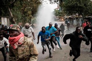 Protesters run away from water released by a police’s water cannon vehicle during a mass rally in Kibera