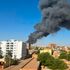 A column of smoke rises behind buildings near the airport area in Khartoum