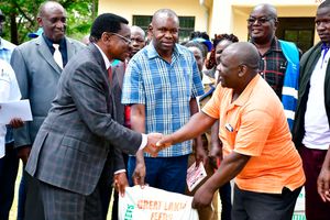 Siaya Governor James Orengo hands feed to a fish farmer