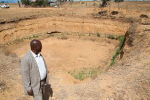Maina Mugo stands in front of a dry water pan at Solio Settlement Scheme