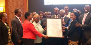 Dr Francis Muthaura receives a portrait at Serena Hotel in Nairobi