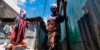 Amina Wanjiru wades through a flooded alleyway in the Soweto