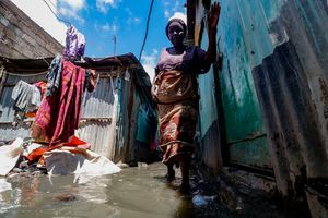 Amina Wanjiru wades through a flooded alleyway in the Soweto