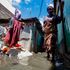 Amina Wanjiru wades through a flooded alleyway in the Soweto