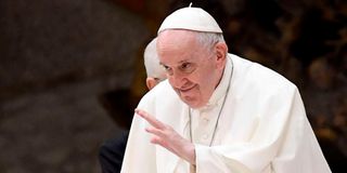 Pope Francis waves to pilgimsat Paul-VI hall in The Vatican.