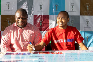 Rohto Mentholatum Sales and Marketing manager, John Macharia (right), signs a sponsorship cheque 