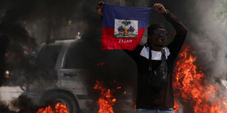 A demonstrator holds up a Haitian flag during a protest against Prime Minister Ariel Henry's