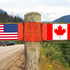 Wooden signpost with two arrows - American and Canadian national flags 