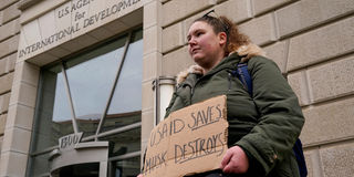 woman holds a placard outside the USAID building