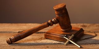 Judge's gavel and cross on wooden table