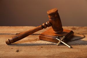 Judge's gavel and cross on wooden table