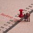 Miniature figure couple Senior Pensioners standing with red pin on ruler