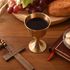 Wine glass and consecrated hosts on wooden table with christian cross 