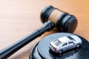 A judge gavel and a miniature car on a wooden table.