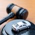 A judge gavel and a miniature car on a wooden table.