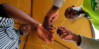 An IEBC official inks thr finger of an inmate at Kamiti Maximum Prison