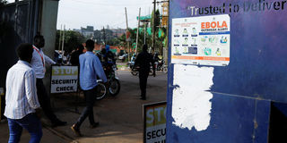 People walk past an advocacy poster against the spread of Ebola virus in Kampala, Uganda