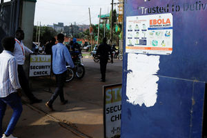 People walk past an advocacy poster against the spread of Ebola virus in Kampala, Uganda