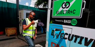 A BasiGo charging station attendant charges EV batteries on an electric bus in Nairobi.